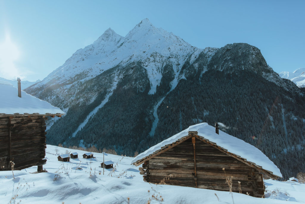 A swiss winter landscape with traditional chalets and mountains in the background.