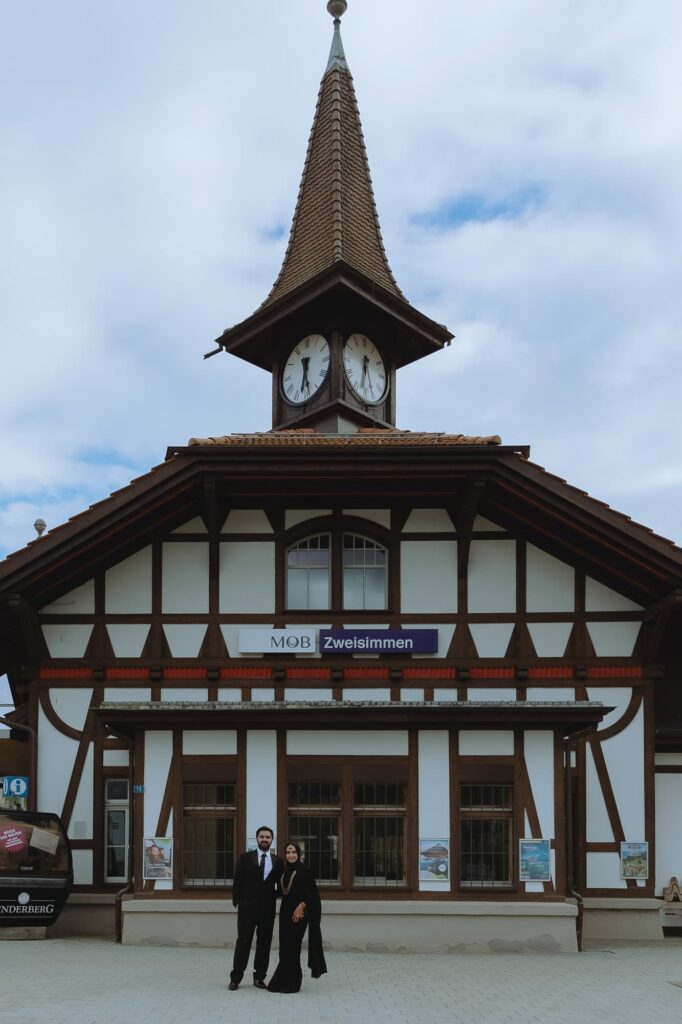 Couple standing in front of Zweisimmen's train station in Switzerland.