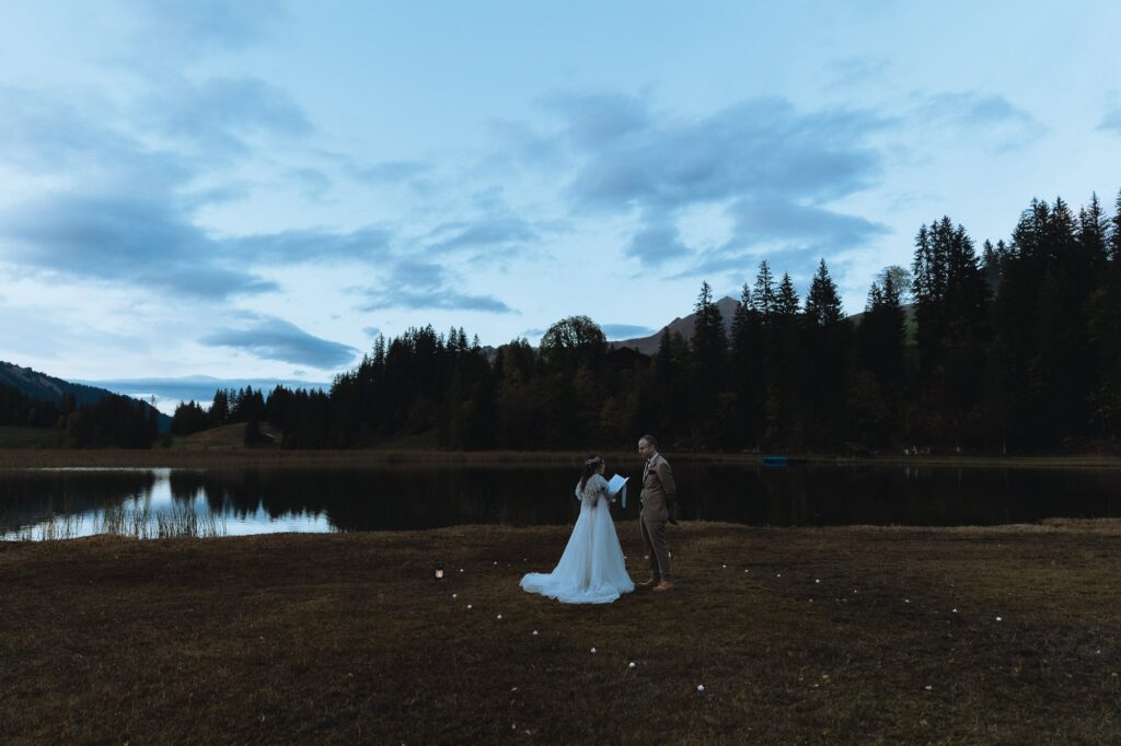 Bride and groom exchanging vows at blue hour by the Lauenensee. Gstaad, Switzerland.