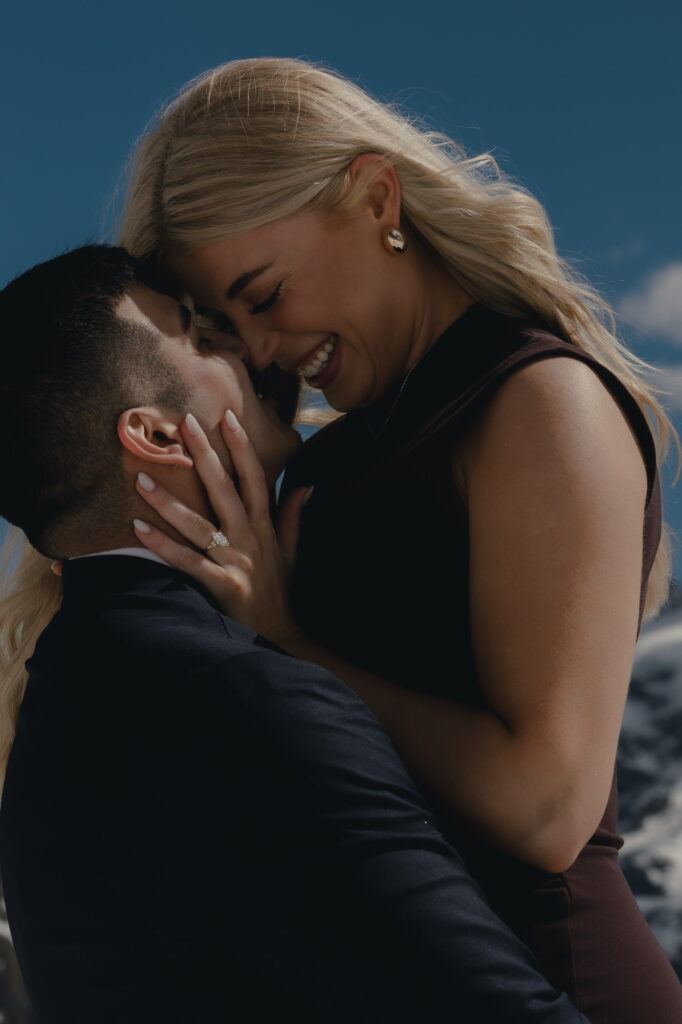 A couple smiling at each other and almost kissing, during their winter proposal near Grindelwald.